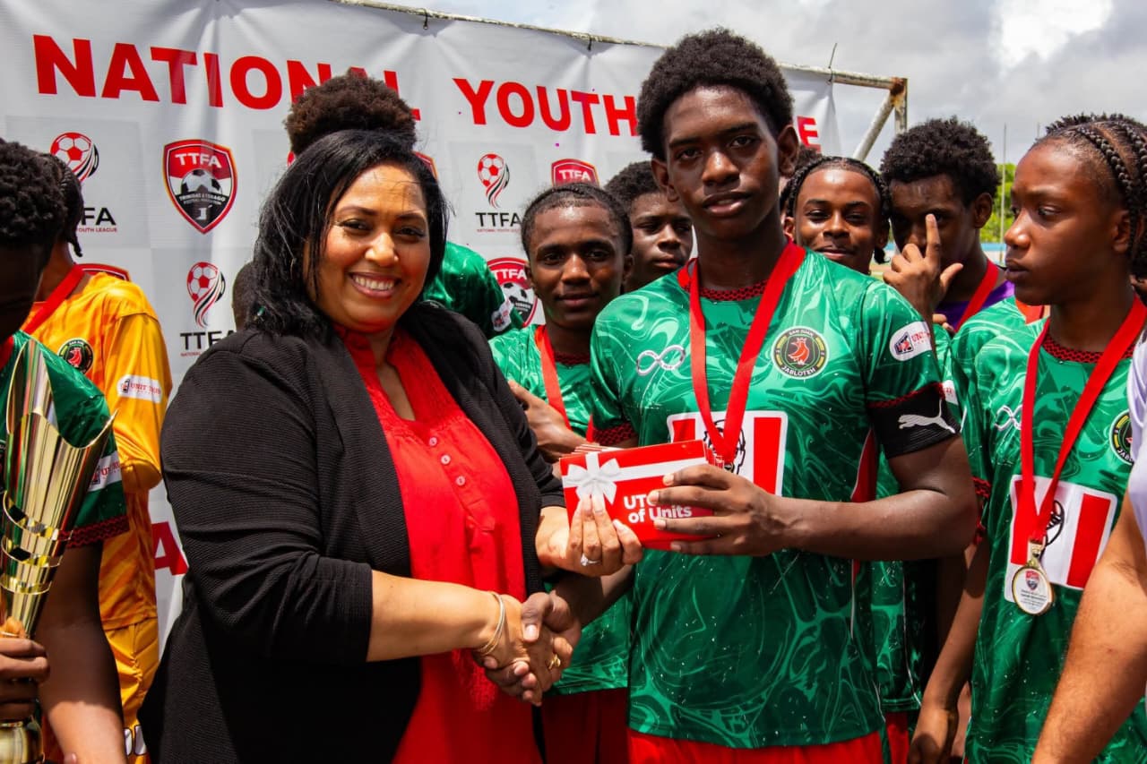 Mrs. Lisa Hitlal-Padilla, Head of Premium Clients, UTC presents Gift of Units to a San Juan Jabloteh player